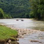 A group of three rafts paddle down a Class 1 river on a rafting trip on the Amazon river.