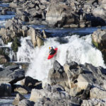A kayaker descending a waterfall on a Class 6 river.